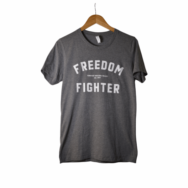 Gray Tennessee Innocence Project Freedom Fighter t-shirt on a wooden hanger